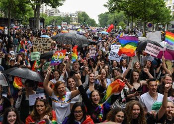 Participants hold placards and flags as they march during the annual Pride Parade in Paris on June 25, 2022. - The Inter-LGBT association who is organising the march say that their aim is to protest against transphysical speech, which they maintain is too often ignored by public authorities. (Photo by Alain JOCARD / AFP)