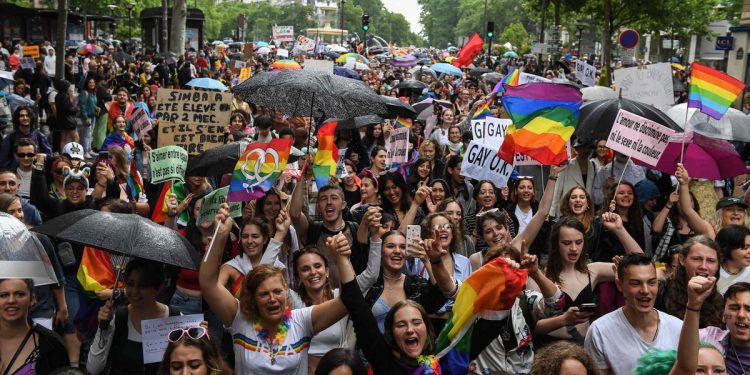 Participants hold placards and flags as they march during the annual Pride Parade in Paris on June 25, 2022. - The Inter-LGBT association who is organising the march say that their aim is to protest against transphysical speech, which they maintain is too often ignored by public authorities. (Photo by Alain JOCARD / AFP)