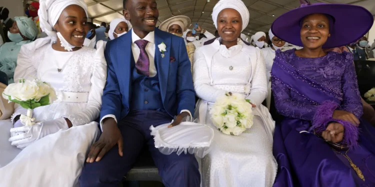 A man with his wife and two of his brides sits inside a marquee ahead of the mass Easter weddings for 3,000 people, some polygamous, at the International Pentecost Holiness Church in Heidelberg, east of Johannesburg, South Africa, Sunday, April 20, 2025. (AP Photo/Themba Hadebe)