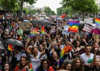 Participants hold placards and flags as they march during the annual Pride Parade in Paris on June 25, 2022. - The Inter-LGBT association who is organising the march say that their aim is to protest against transphysical speech, which they maintain is too often ignored by public authorities. (Photo by Alain JOCARD / AFP)
